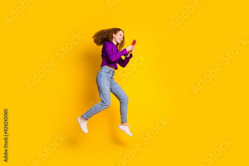 Full body photo of pretty young girl running hold device wear trendy violet outfit isolated on yellow color background