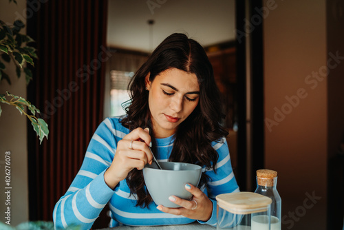One young caucasian woman is eating corn flex breakfast at home before work	
