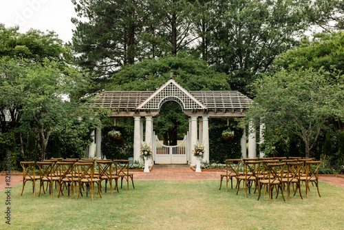 Outdoor wedding ceremony setup with chairs and a white pergola