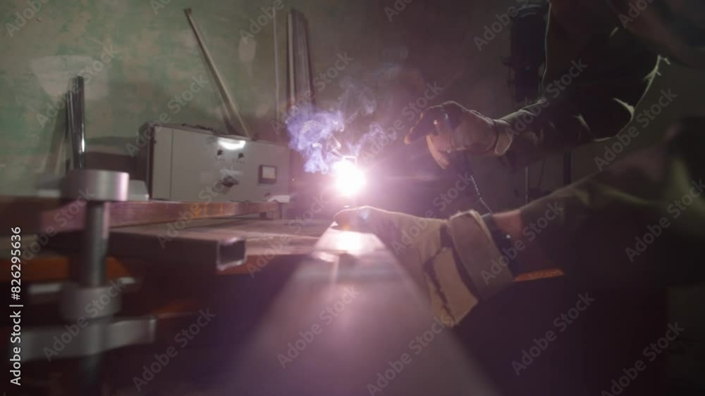 Metalworker using welding machine on iron surface, smoke, sparks and flashing lights around, man worker welding steel material. Metalworker using welding machine on iron surface, smoke, sparks and flashing lights around, man worker welding steel material.