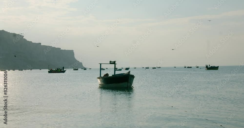 boats docked on sea and birds flying above at sunset with mount in the background in Gwadar Beach boats docked on sea and birds flying above at sunset with mount in the background in Gwadar Beach