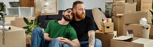 Canvas Print Couple of men nestled atop couch amidst new home move-in bustle.