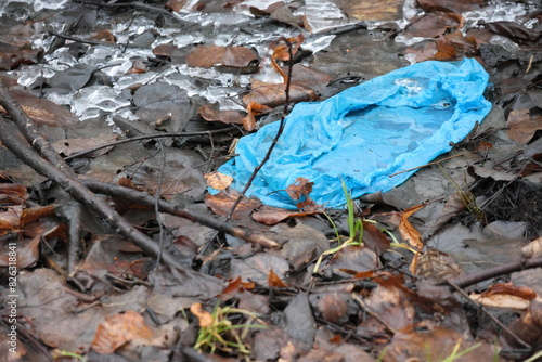 A blue unattractive shoe cover thrown into the naturally brown vegetation of Sweden. photo