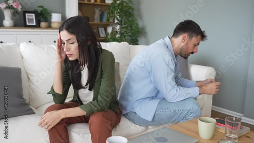 Young couple having relationship difficulties and arguing at home. Two people man and woman sitting on sofa, not talking after argue, feeling depressed and insulted, not talking. photo