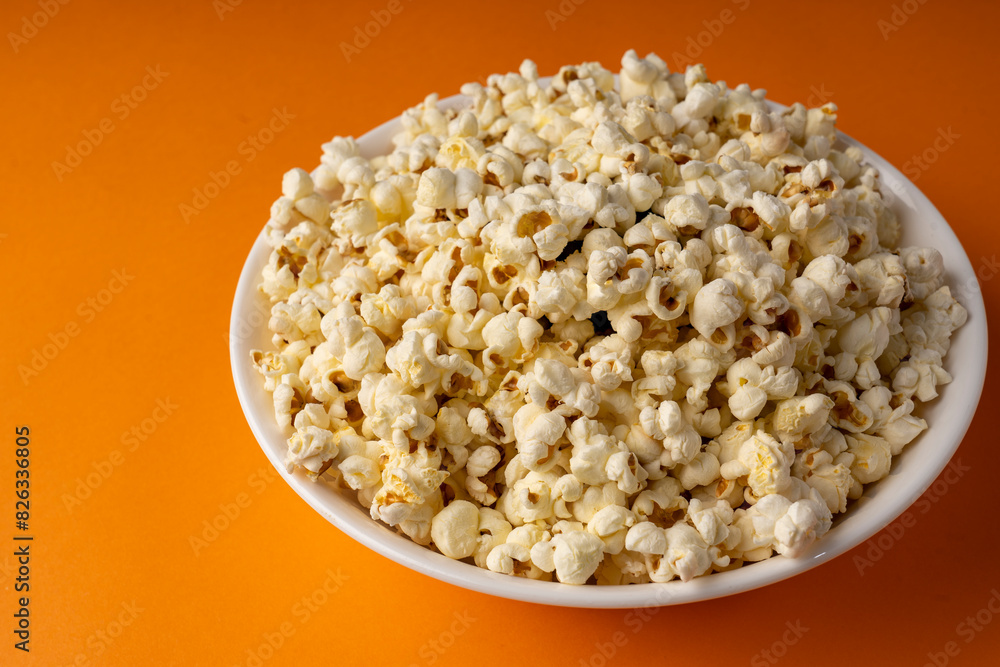 White bowl of popcorn on an orange table. White bowl of popcorn on an orange table.