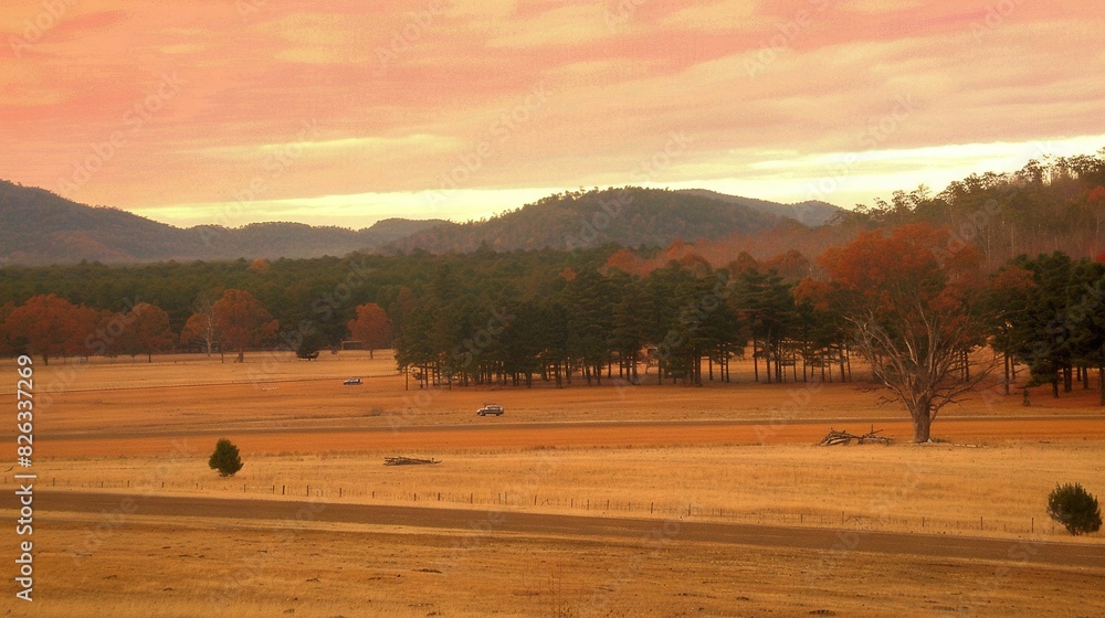 Obraz premium A field with trees, mountains, pink sky, orange background