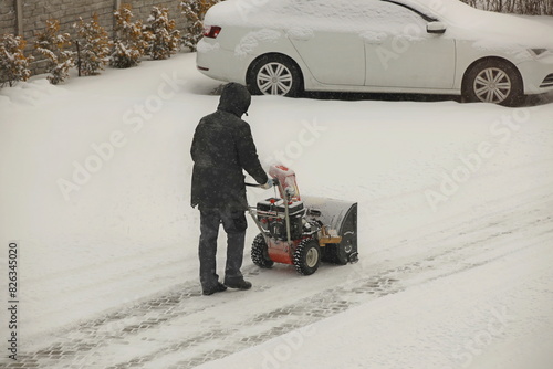 Robotnik clears snow from the sidewalk with a manual snowplow driven by a gasoline engine. Fighting the after-effects of a snowstorm. The power of the winter element