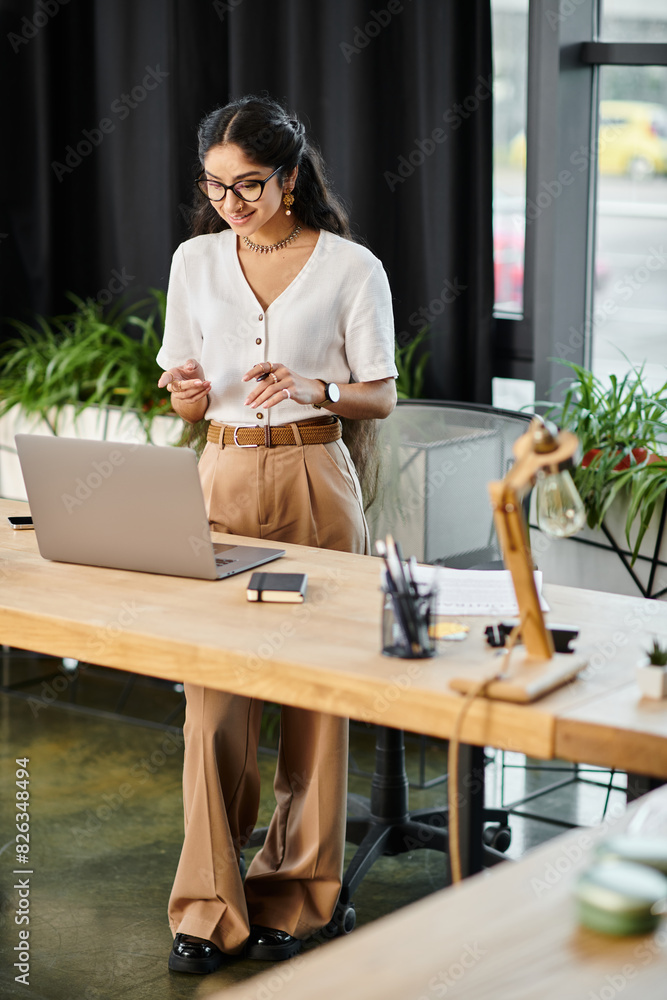 Young indian woman energetically working on a laptop at a stylish desk. Young indian woman energetically working on a laptop at a stylish desk.