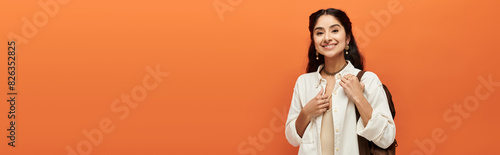 A indian woman beams with joy on a vibrant orange backdrop. © LIGHTFIELD STUDIOS