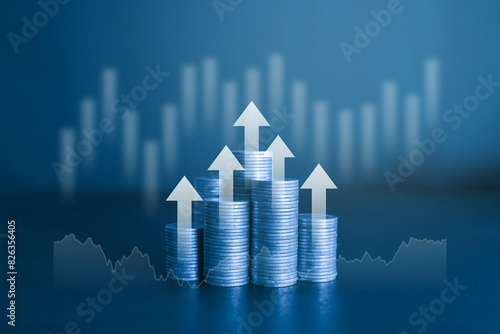 Stack of money coins with white up rising arrow and graph in the background. Business and financial concept with blue color filter. 
