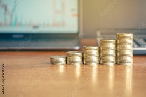 Up stack golden money coins with laptop computer and calculator on a table representing money, finance, and investment. Business and financial concept. 
