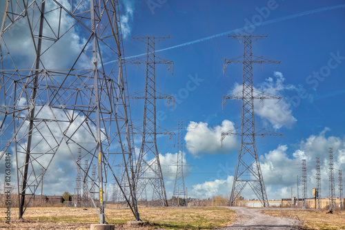 A number of hydro electricity towers or pylons carrying high power lines into the distance, blue sky, clouds, nobody