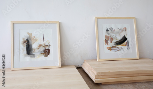 Modern art. Closeup view of contemporary abstract paintings with a wooden framing, in the art studio. Beautiful brushwork, texture and pale color pattern.	