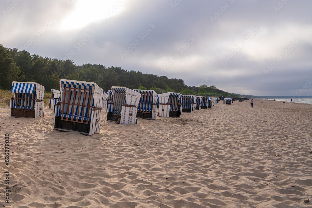 .Picturesque landscape at sunset of a sandy beach on the Baltic Sea. Traditional North German wind and sun protection, sun lounger, strandkorb. Walking tourists. Relax. Baltika, Usedom .Picturesque landscape at sunset of a sandy beach on the Baltic Sea. Traditional North German wind and sun protection, sun lounger, strandkorb. Walking tourists. Relax. Baltika, Usedom