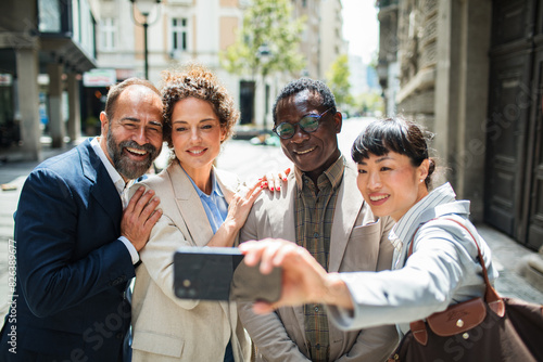 Group of diverse business people taking a selfie together on a sunny city street photo
