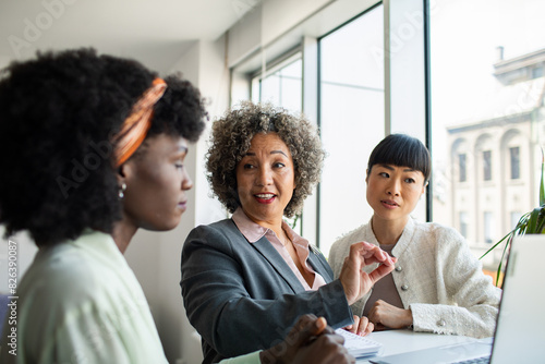 Diverse young female colleagues with laptop in modern office photo