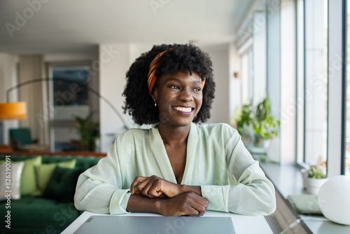 Portrait of a smiling young Black woman sitting at a desk in a modern home office photo