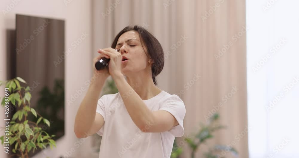 Excited caucasian woman using tv remote as microphone dancing and singing in living room at home Excited caucasian woman using tv remote as microphone dancing and singing in living room at home
