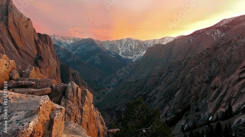   A panoramic shot of snow-capped mountains bathed in sunset hues from their summit peaks
