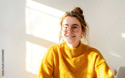 Smiling woman looks at the camera in yellow sweather. Happy female occupation. photo
