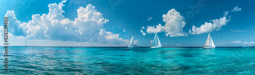 Panoramic view of a turquoise ocean with distant sailboats and white clouds. This scene would be perfect for a summer vacation and travel poster design. © PHTASH