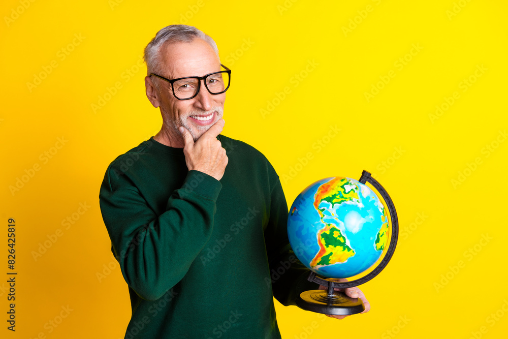 Photo portrait of handsome retired man hold thoughtful earth globe wear trendy green outfit isolated on yellow color background Photo portrait of handsome retired man hold thoughtful earth globe wear trendy green outfit isolated on yellow color background