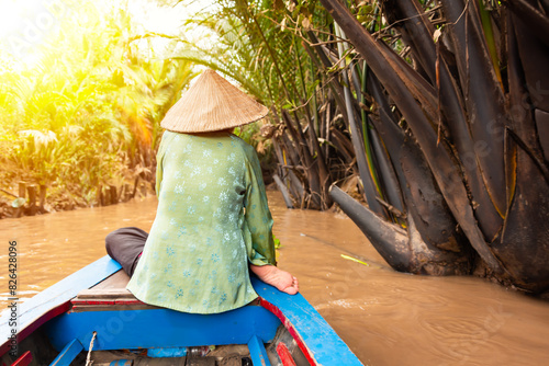 Woman with asian hat rowing in a boat on jungle river