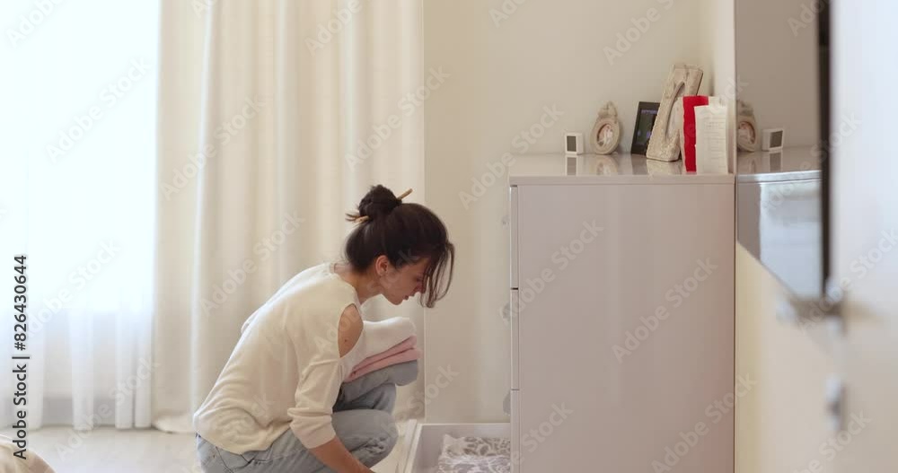 caucasian woman opening a drawer and putting a bath towels into caucasian woman opening a drawer and putting a bath towels into