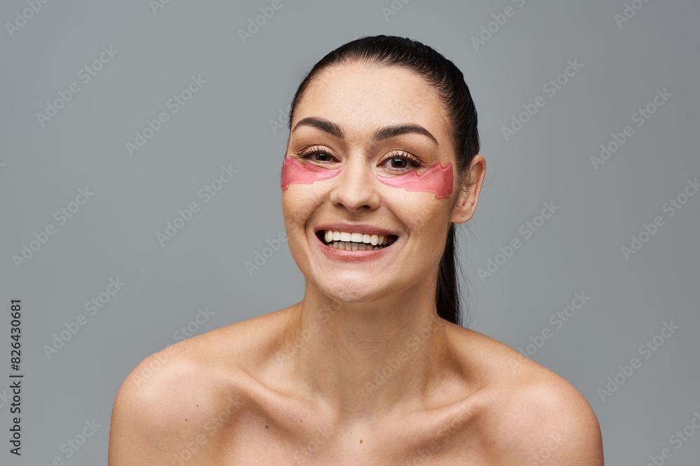 Cheerful woman with pink eye patches enhancing her face. Cheerful woman with pink eye patches enhancing her face.