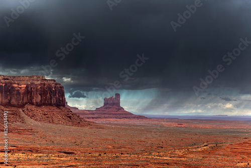 Fotografie Monument Valley during a dramatic rainstorm shows a deep, dark passing cloud layer, an ominous scene not observed too often