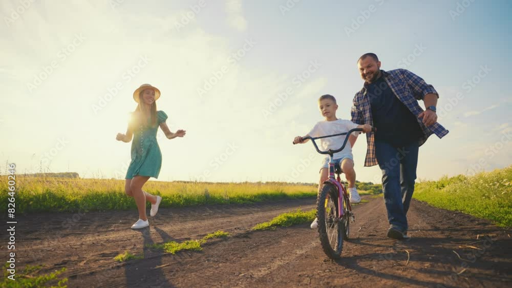 Childhood bike concept. Mother and dad teaching son to ride bicycle. Young family teaching son to ride bike first time on countryside rural road at sunset. Happy kid concept. The best moments together Childhood bike concept. Mother and dad teaching son to ride bicycle. Young family teaching son to ride bike first time on countryside rural road at sunset. Happy kid concept. The best moments together