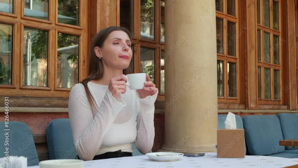 Beautiful woman drinking coffee in outdoor cafe, above view. Camera moving around her Beautiful woman drinking coffee in outdoor cafe, above view. Camera moving around her