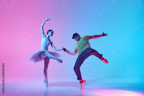 Elegance of ballet meets the vibrant energy of hip-hop. Young ballerina dancing with man, break dancer on gradient background in neon light. Concept of classical and modern dance, performance