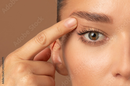 Obraz na płótnie Closeup of young European woman pointing to the wrinkles on the upper eyelid, touching face