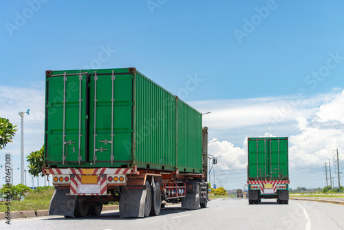 Bild auf Leinwand Two green container trucks driving on a highway under a clear blue sky, emphasizing transportation and logistics