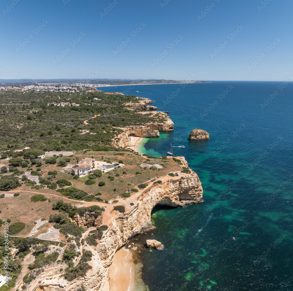 Aerial view of rugged coastal cliffs and clear blue waters at Praia da Marinha, Algarve region, Portugal. Aerial view of rugged coastal cliffs and clear blue waters at Praia da Marinha, Algarve region, Portugal.
