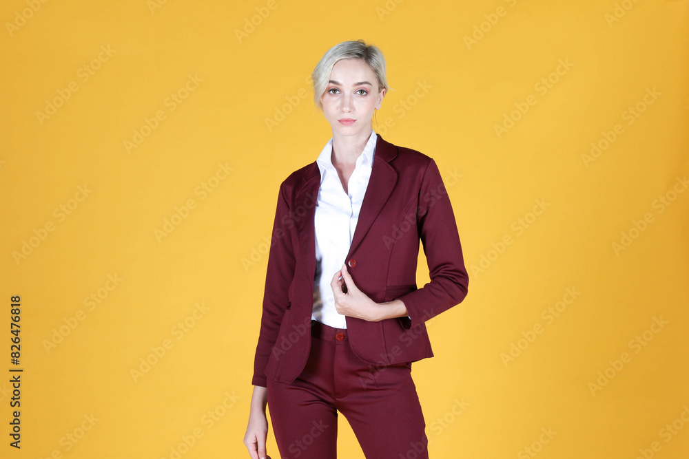 Portrait of young businesswoman smiling and raise her hand to the brown suit over yellow background Portrait of young businesswoman smiling and raise her hand to the brown suit over yellow background