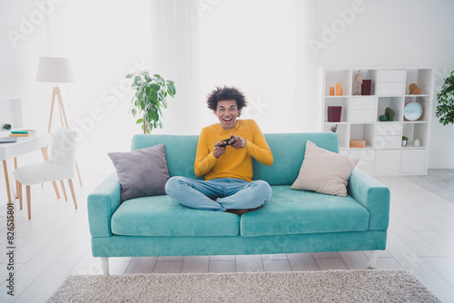Full size photo of nice young man play video games wear yellow pullover white interior apartment indoors