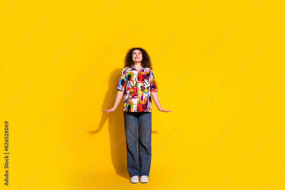 Full length photo of lovely lady girlish posing look up empty space dressed colorful print garment isolated on yellow color background Full length photo of lovely lady girlish posing look up empty space dressed colorful print garment isolated on yellow color background