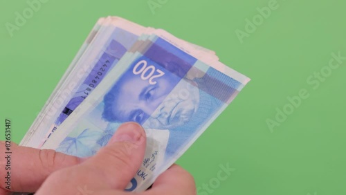 Close-up of male hands counting a stack of hundred Israeli shekels,  a businessman is counting cash. The concept of investment, money exchange, bribes or corruption. Slow Motion