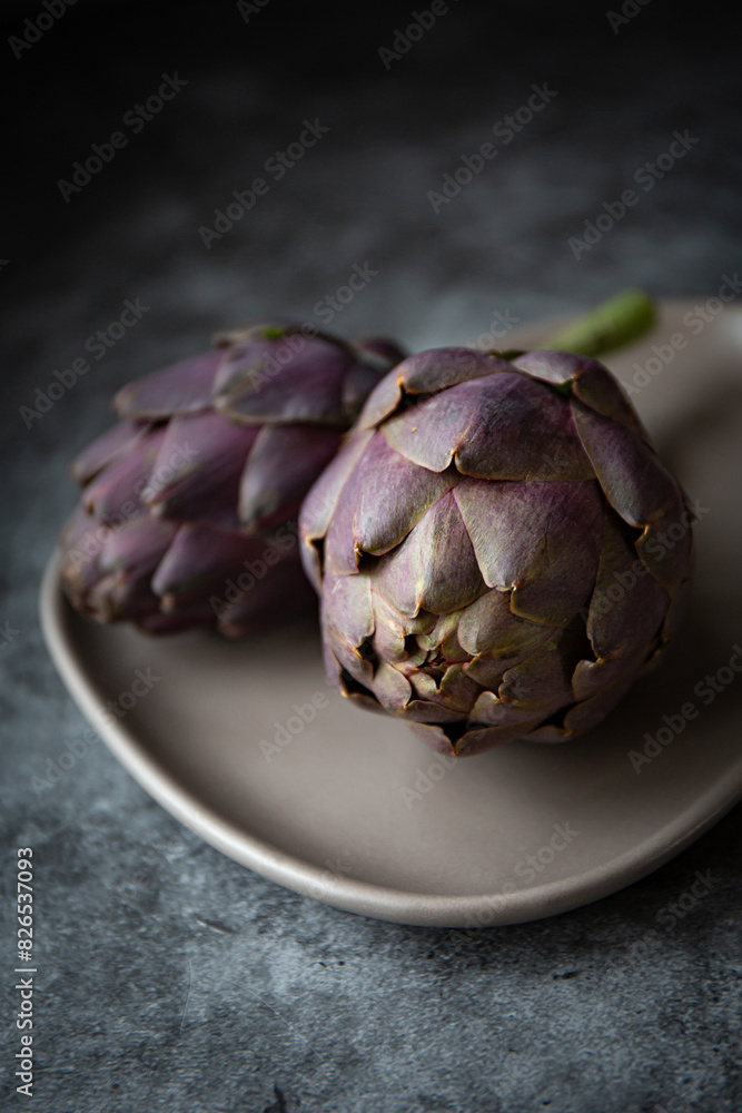 Fototapeta premium Fresh purple artichokes on dark background 