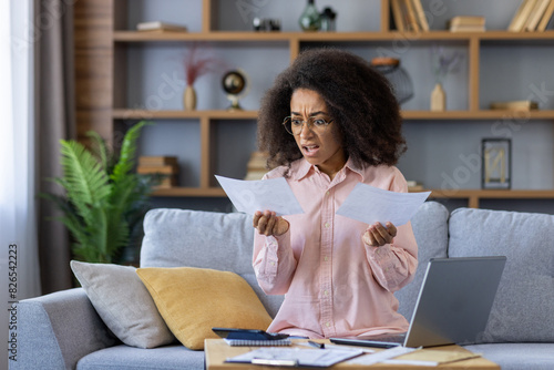 Upset and distressed woman working with documents and papers at home, paying utility bills and loan payments, shocked by high interest rates for insurance and mortgage
