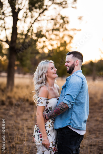 Young couple standing together in paddock laughing photo