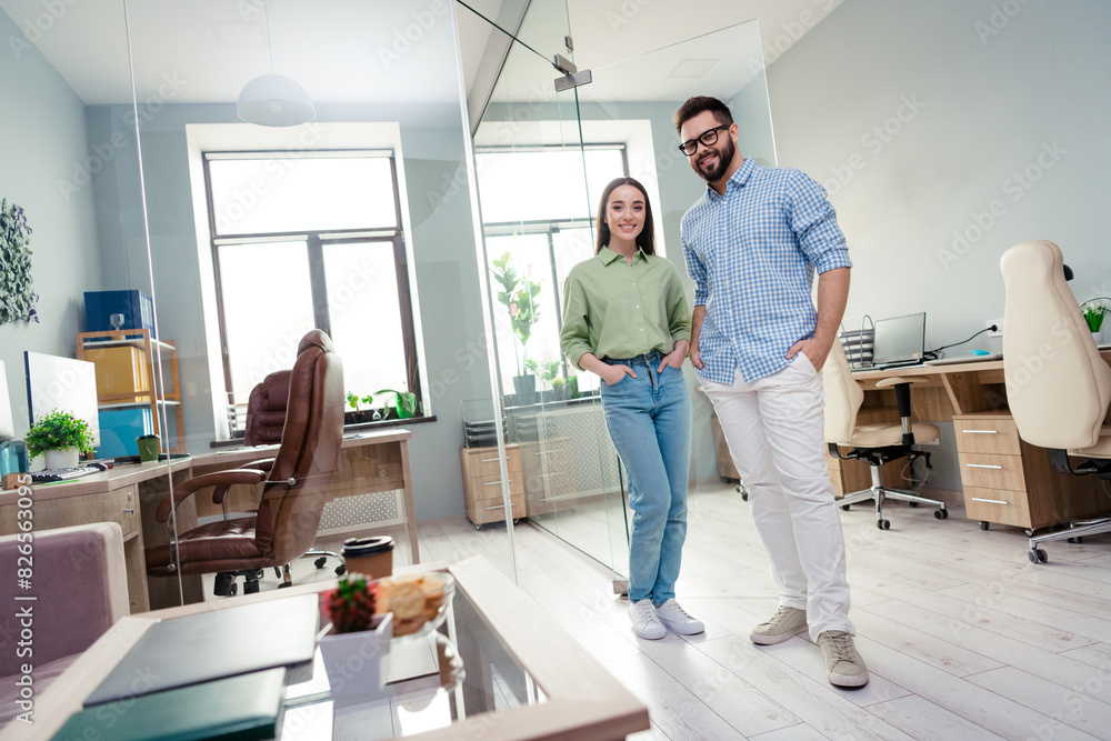 Photo of two people business partners stand near glass door invite new company staff in workplace Photo of two people business partners stand near glass door invite new company staff in workplace
