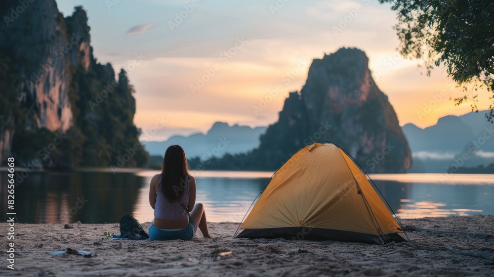 A woman sits on the beach next to a yellow tent A woman sits on the beach next to a yellow tent