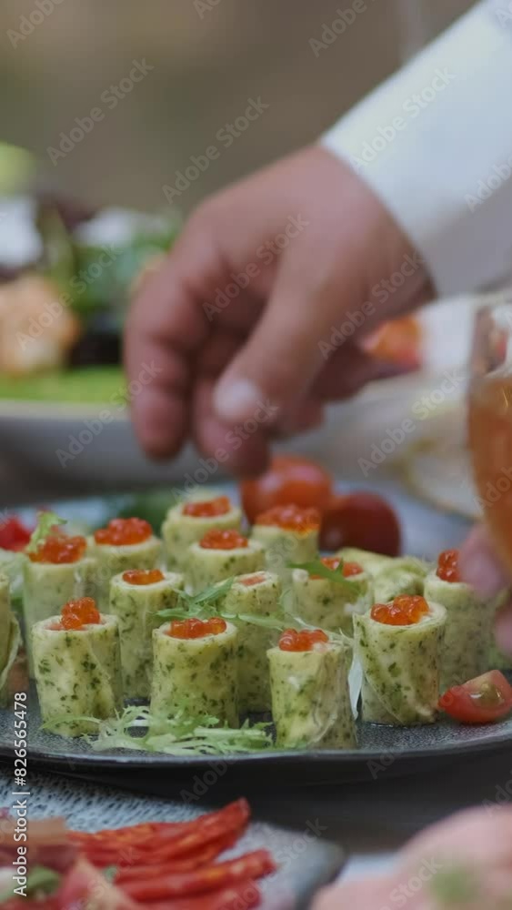 The waiter places a plate of red caviar in pancakes on a beautifully decorated holiday table in pink colors.
