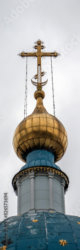 Fragment of the dome of an Orthodox church with a gilded cross. Orthodox cross on the dome of a Christian church, bottom view. Golden Orthodox cross of the temple against the background of a blue sky 