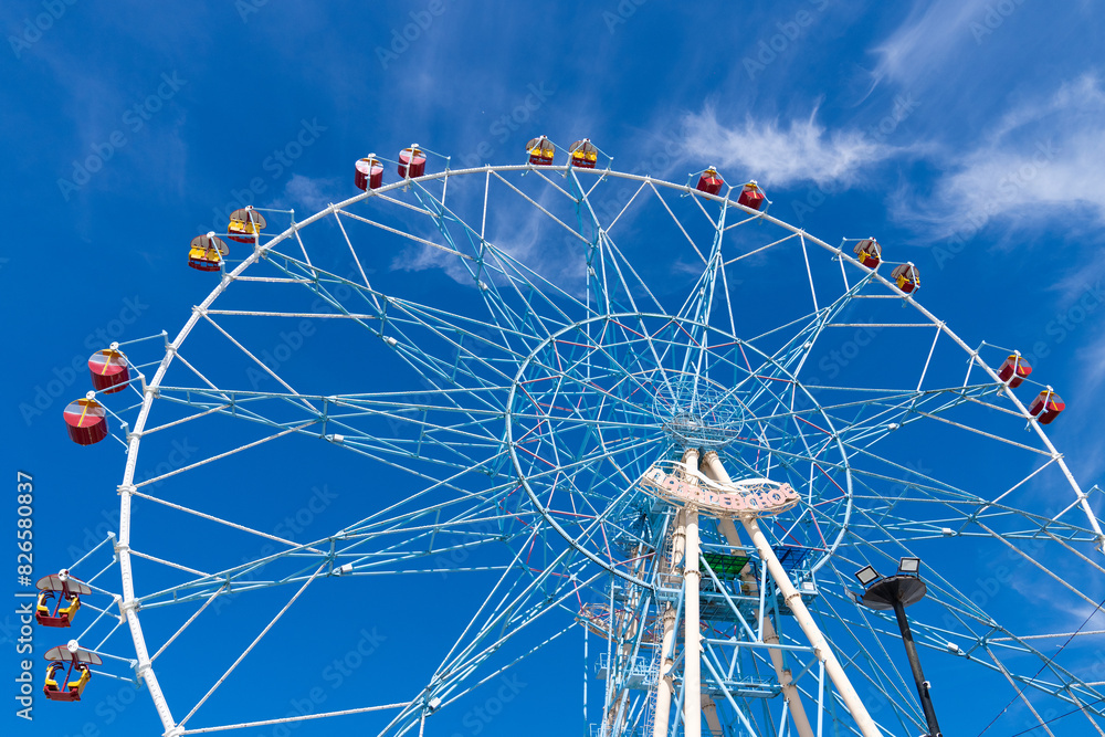 Fototapeta premium Ferris wheel against the blue sky. Modern Ferris wheel. Big, tall white Ferris wheel in front of a perfect blue sky. Happy summer vacation feelings. Sochi Ferris wheel 