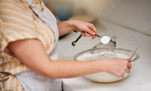 Hands, kitchen and flour for baking, home and glass bowl for dessert or small business. Baker, ingredients and measurement with spoon, house or startup bakery for recipe prepare or sweet food process photo