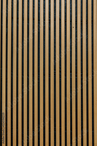 A wall of vertical wooden strips in warm colour, interior decoration background. Upright shape.